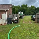A vacuum truck from Septic Panther in the middle of a residential backyard lush with green grass.
