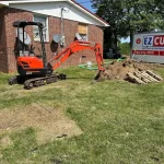 Excavator in a backyard digging up dirt.