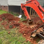 An excavator plows a residential backyard.