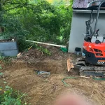 Excavator plowing dirt in a residential backyard.